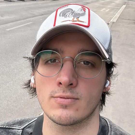 Tomás, wearing a cap and round glasses, on a street in Graz